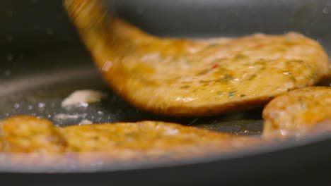 chef using tongs to flip over delicious chinese chicken steak fillets cooking in hot oil in pan. food photography footage 4k.