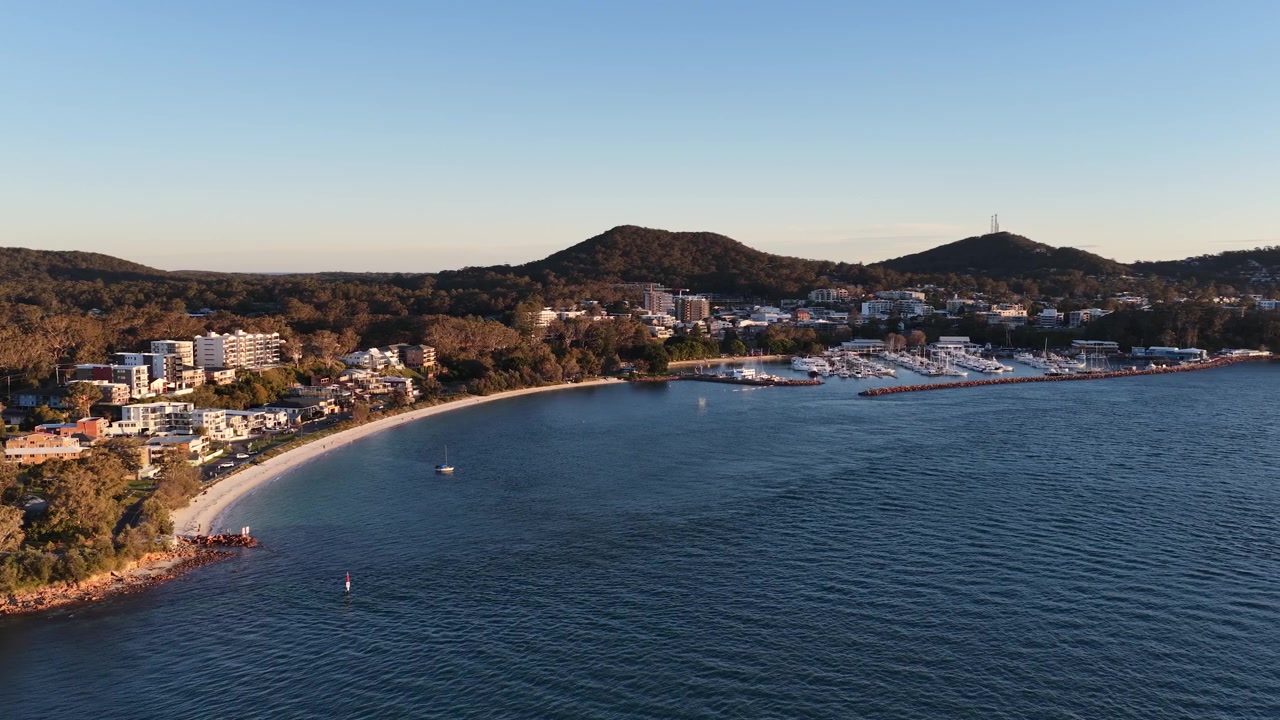 Veduta aerea di una città costiera e di un porto turistico al tramonto.