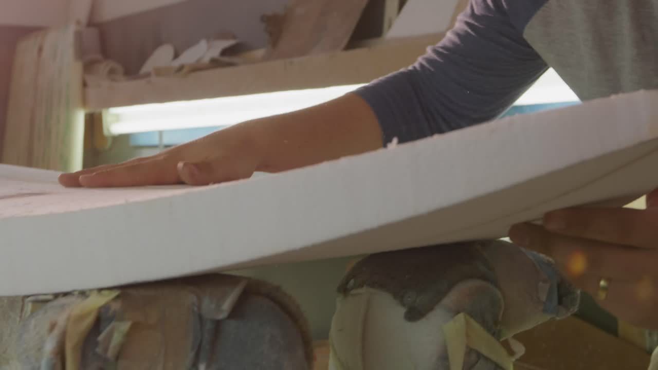 un uomo che fa le tavole da surf nel suo laboratorio