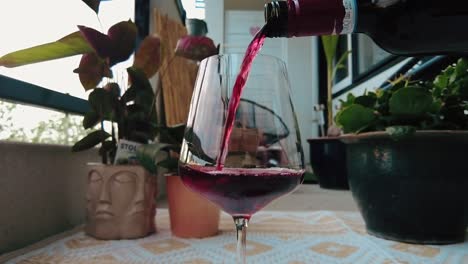 red-wine-being-poured-in-a-glass-in-slow-motion-outdoor-on-deck-balcony