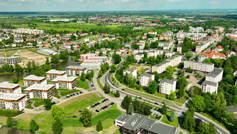 Perspectiva-Aérea-De-Iława,-Pasando-Desde-La-Parte-Urbana-De-La-Ciudad-Hasta-La-Costa-Del-Lago