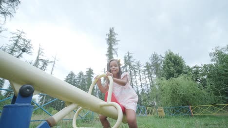 a pregnant mother and her young daughter enjoy playful time together at a playground in the park, surrounded by trees and greenery