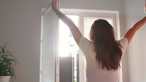 vista trasera de una mujer joven estirándose en el dormitorio