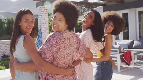 portrait of happy diverse female friends embracing and smiling at swimming pool party