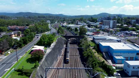 drone aerial city rail train on railway tracks leaving gosford bridge platform station buildings narara wyoming central coast nsw australia 4k