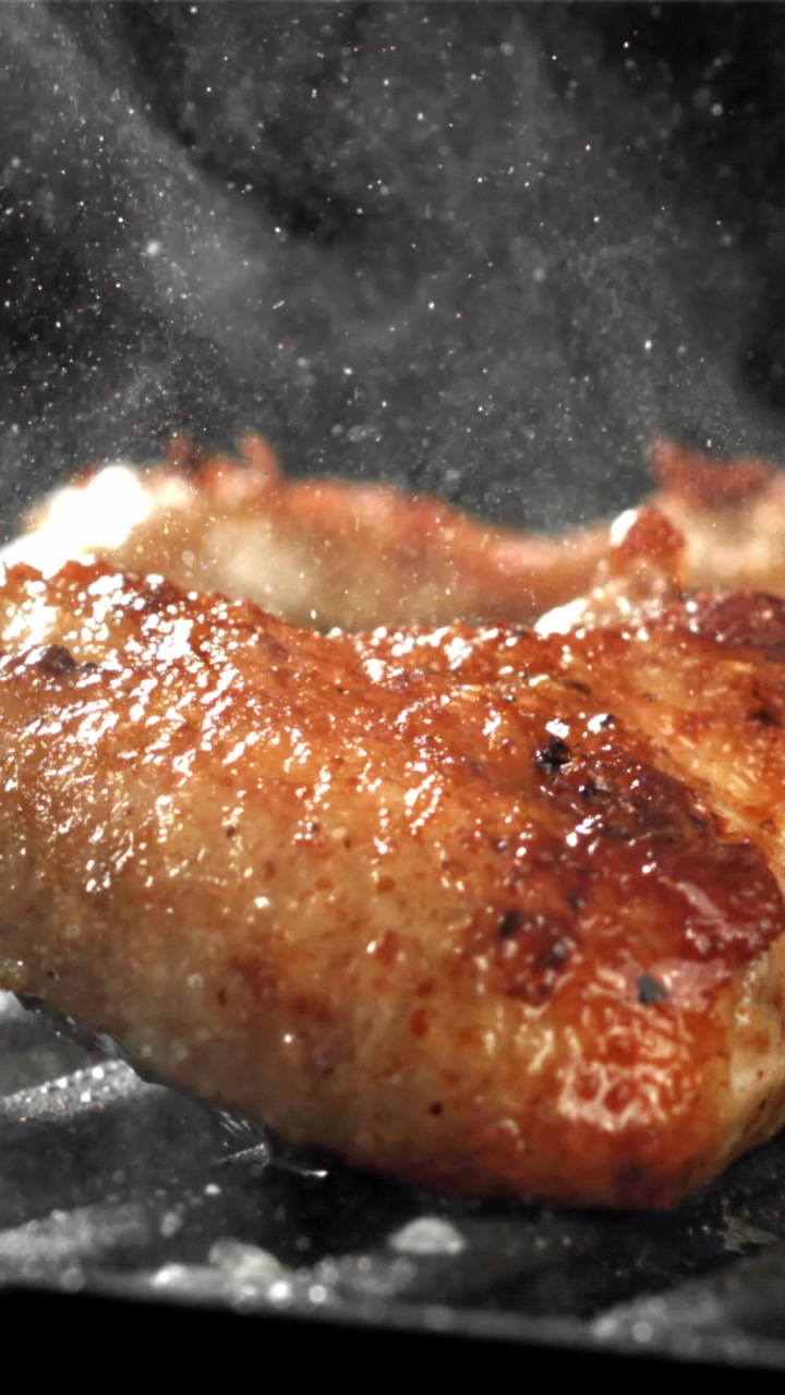 Nærbillede af kød der syder og ryger på en varm grill