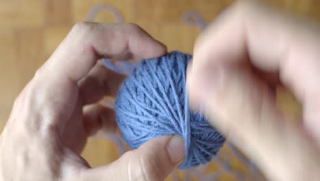 hand finishing winding ball of blue wool