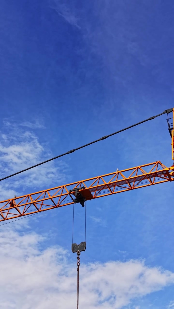 Gru a torre di costruzione domina il paesaggio urbano sotto un cielo azzurro limpido