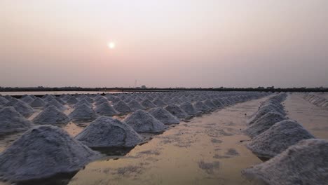 aerial drone over piles of sea salt ready for collection with sunset, thailand