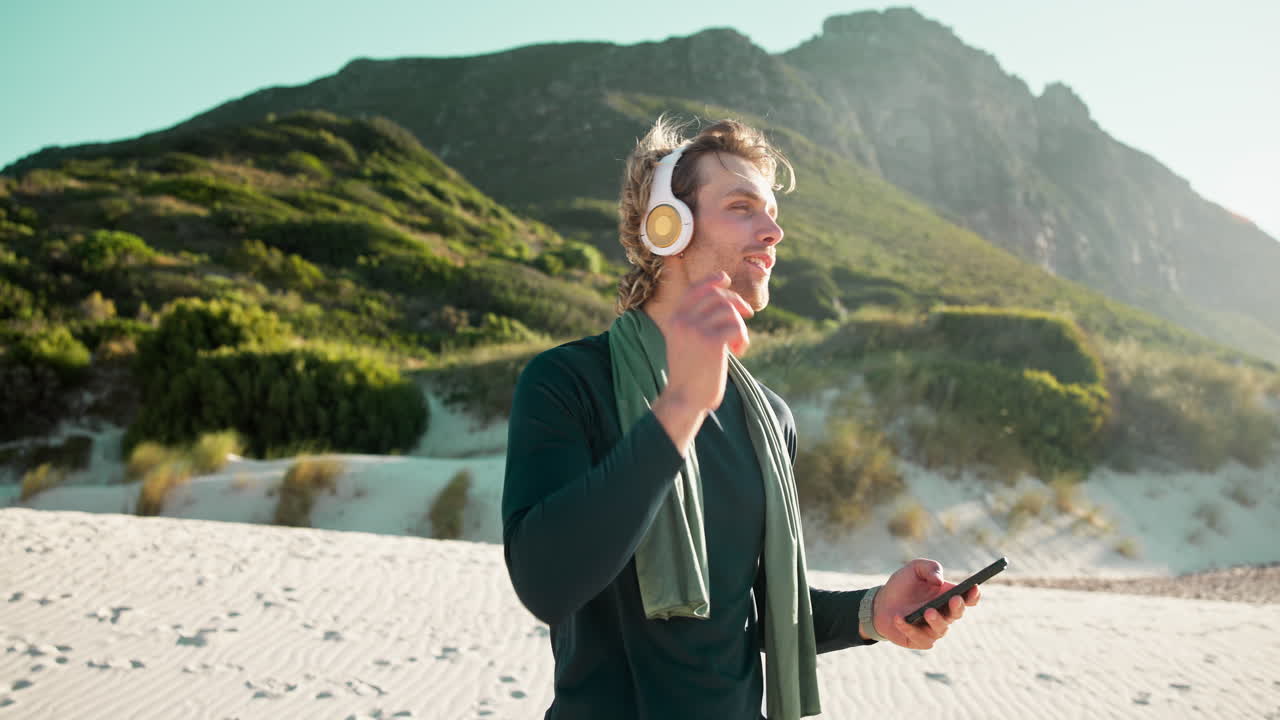 Giovane Uomo che Ascolta Musica al Telefono in Spiaggia.