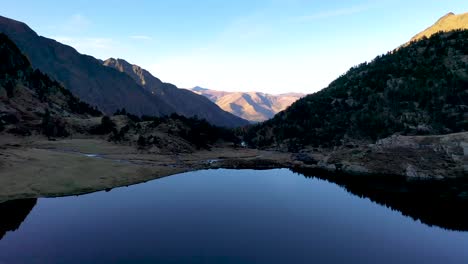 Calm-reflecting-Lac-d'Espingo-mountain-lake-located-in-Haute-Garonne,-Pyrénées,-France,-Aerial-low-flyover-shot