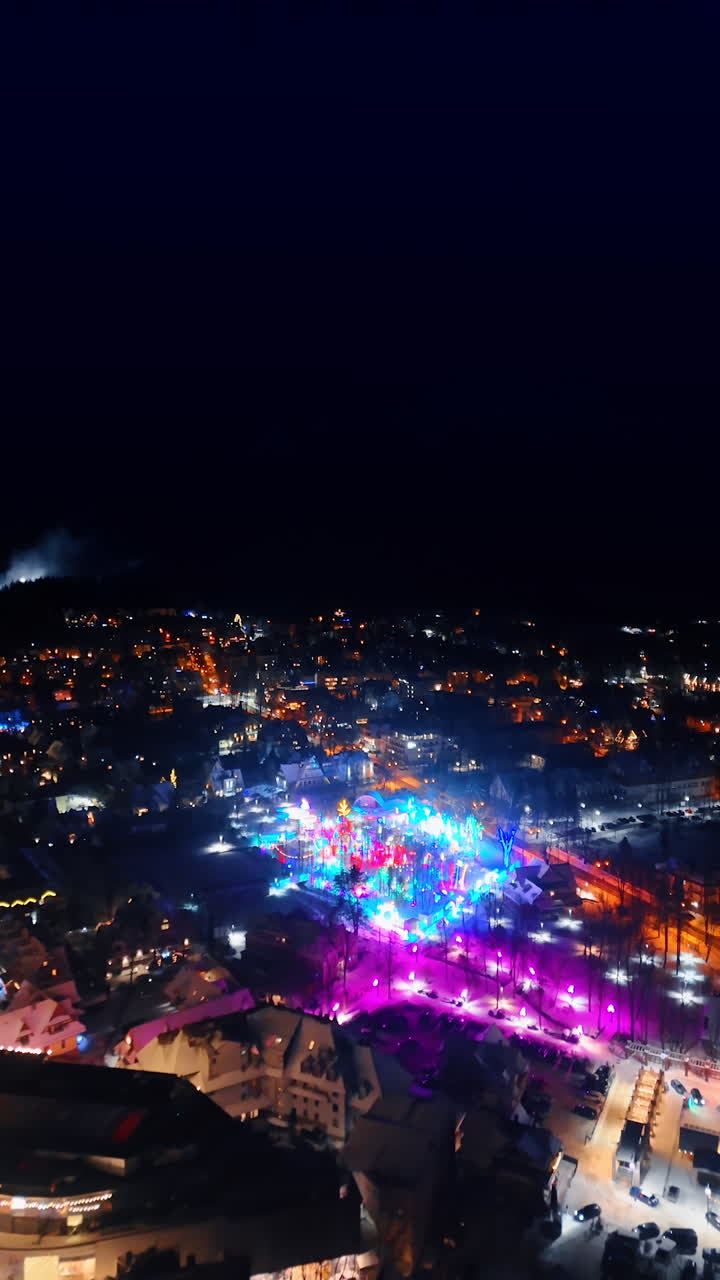 Beautifully decorated center of Zakopane, Poland with festive lights on. Night scenery of the town from top view. Vertical video.