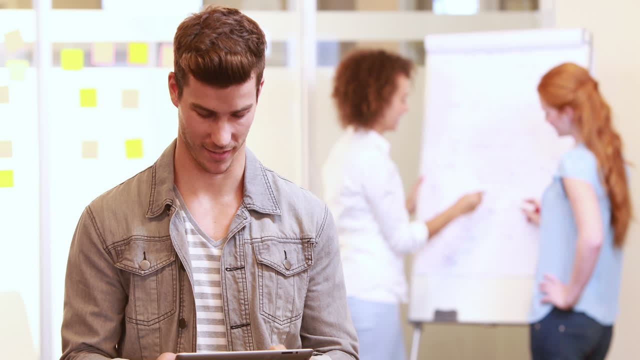 hombre de negocios casual usando la tableta delante de sus colegas
