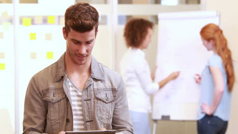 hombre de negocios casual usando la tableta delante de sus colegas