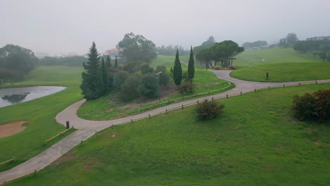 misty greens golf course stretching at landscape drone shot. fairway