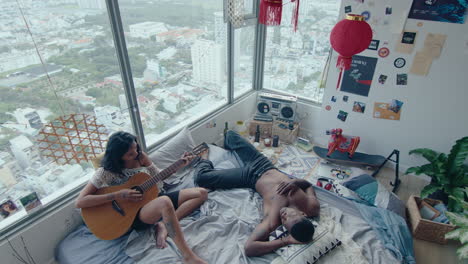 young couple playing the guitar and chilling in the bedroom