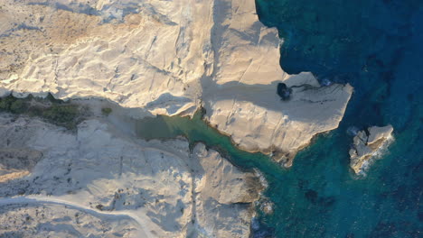 aerial: top down panoramic view of sarakiniko beach in milos island, cyclades, greece during sunrise