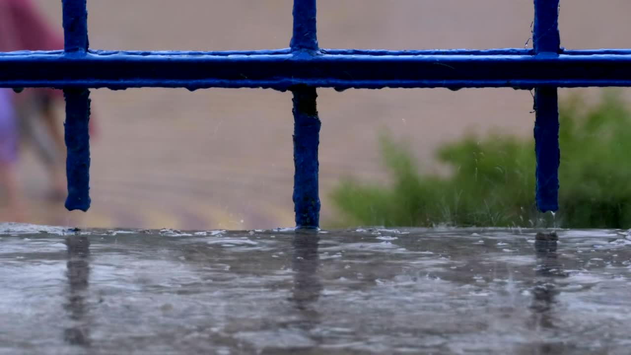 비가 내리는 거리의 배경에 창문, 발코니 또는 레일링으로 흘러내리는 물방울