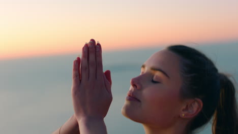 healthy woman meditating on mountain top practicing mindfulness at sunrise