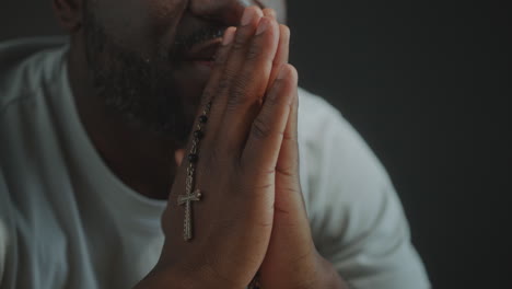 religious black man holding cross and praying to god