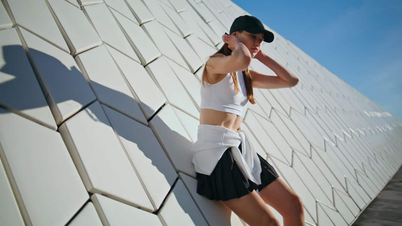 Sport model posing wall with geometric texture basking in sunlight closeup