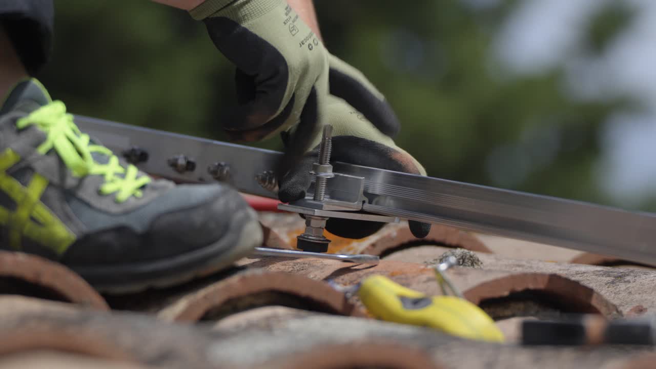 worker tightening metal bolts with his hands and a spanner on a rooftop