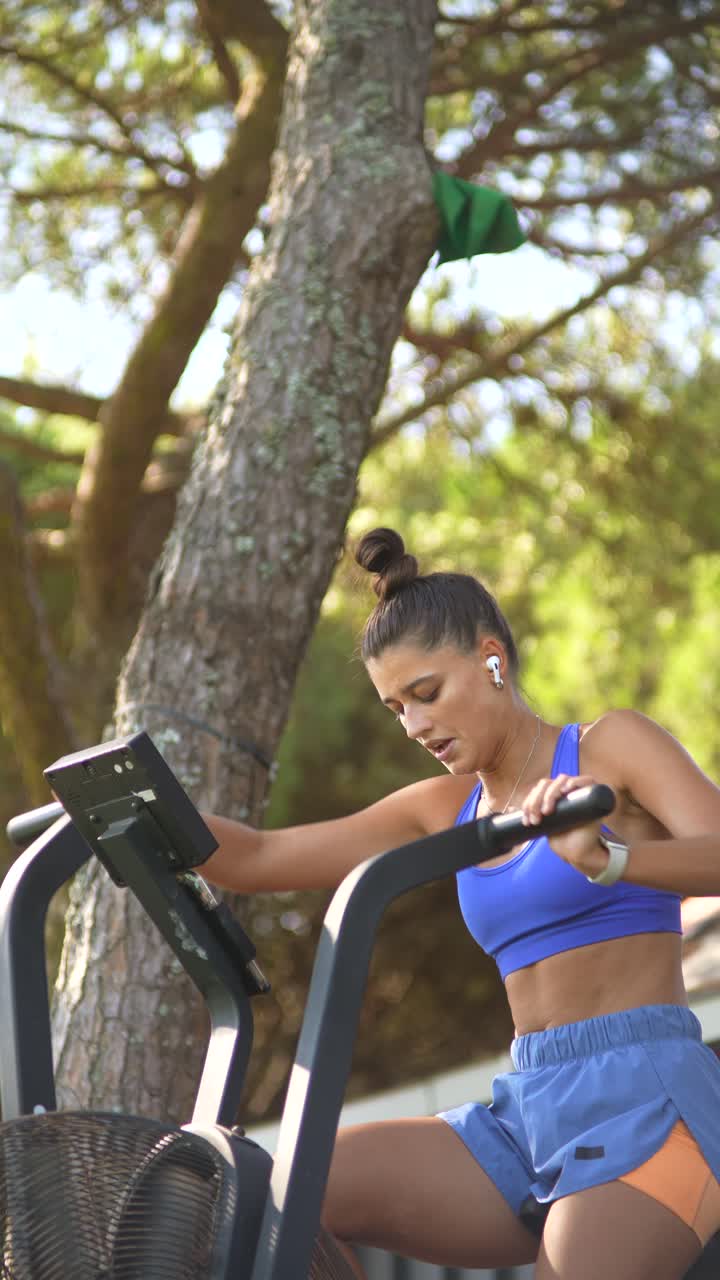 Woman exercising on air bike outdoors