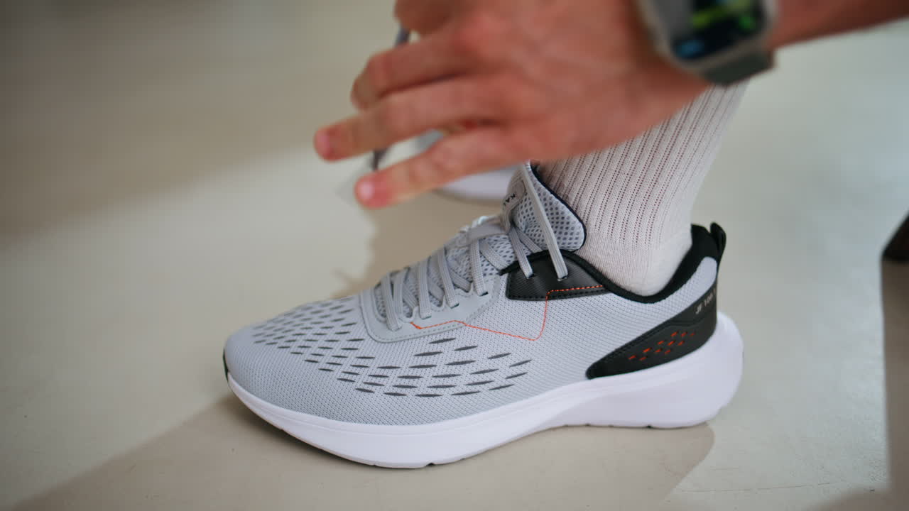 Primo piano di mani maschili che allacciano le scarpe da ginnastica in preparazione all'attività sportiva al chiuso