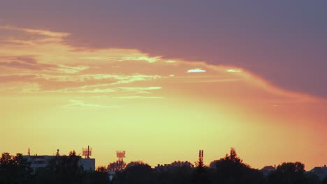 lapso de tiempo de la hermosa puesta de sol roja escénica sobre la ciudad con el sol brillando a través de las nubes, plano general