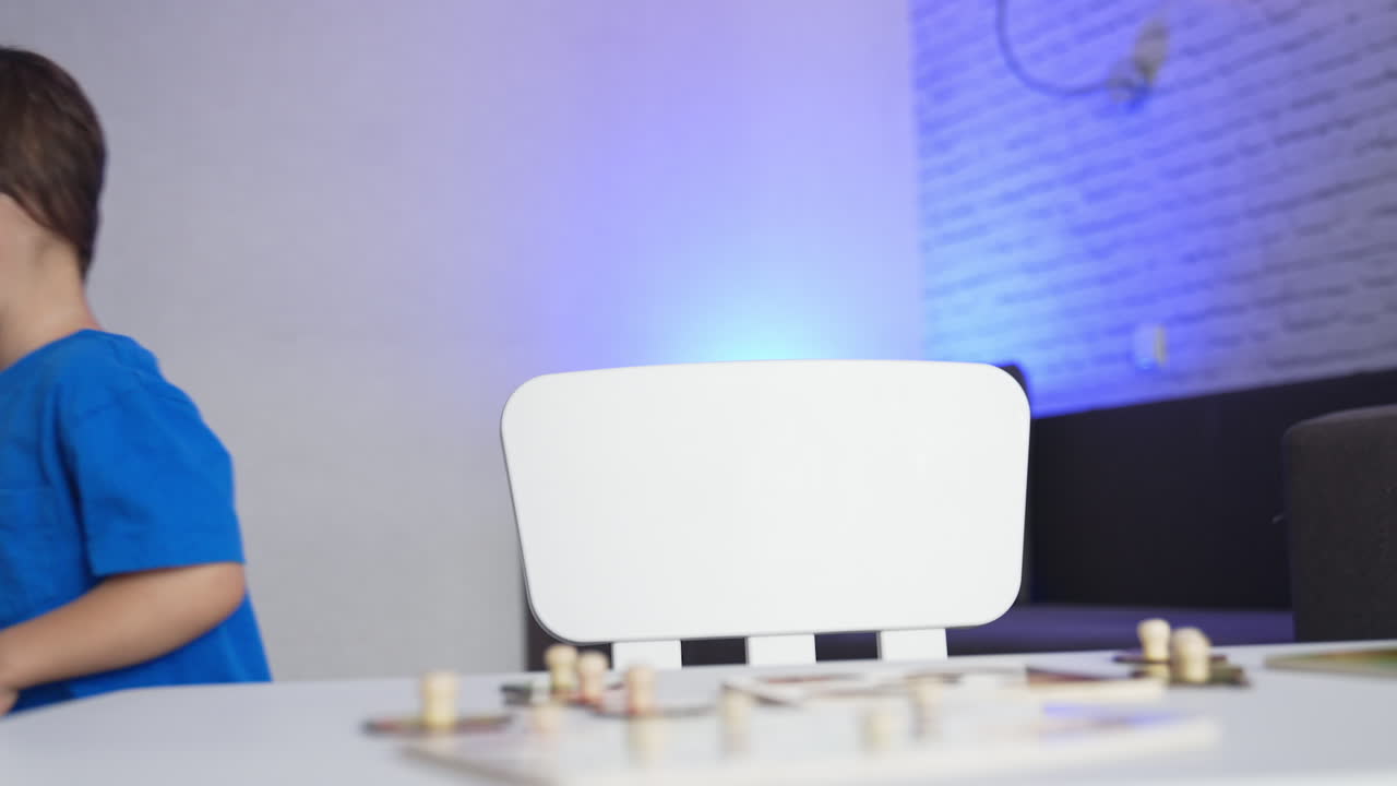 Caucasian baby boy playing with his toys at desk. Kid finishes a game and stands up and leaves.