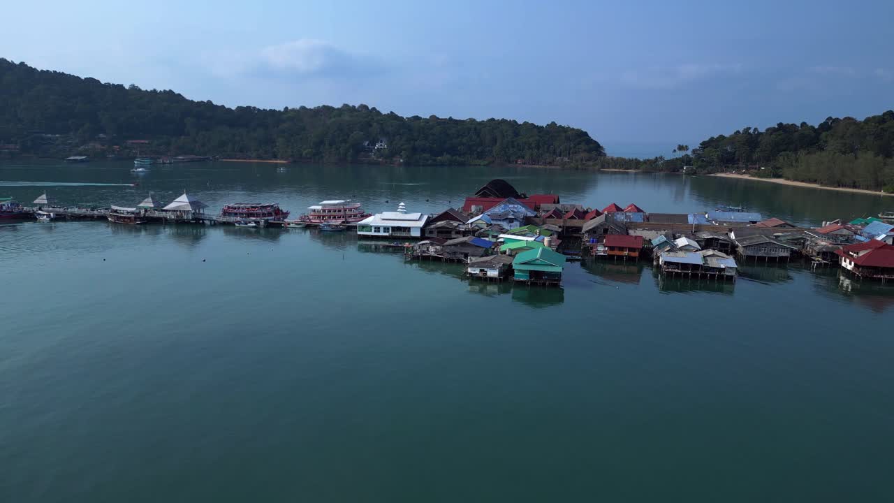 Bang Bao Pier floating village in Koh Chang island, Thailand, showing colorful houses and boats sailing in turquoise water. Perfect aerial view flight static tripod hovering drone