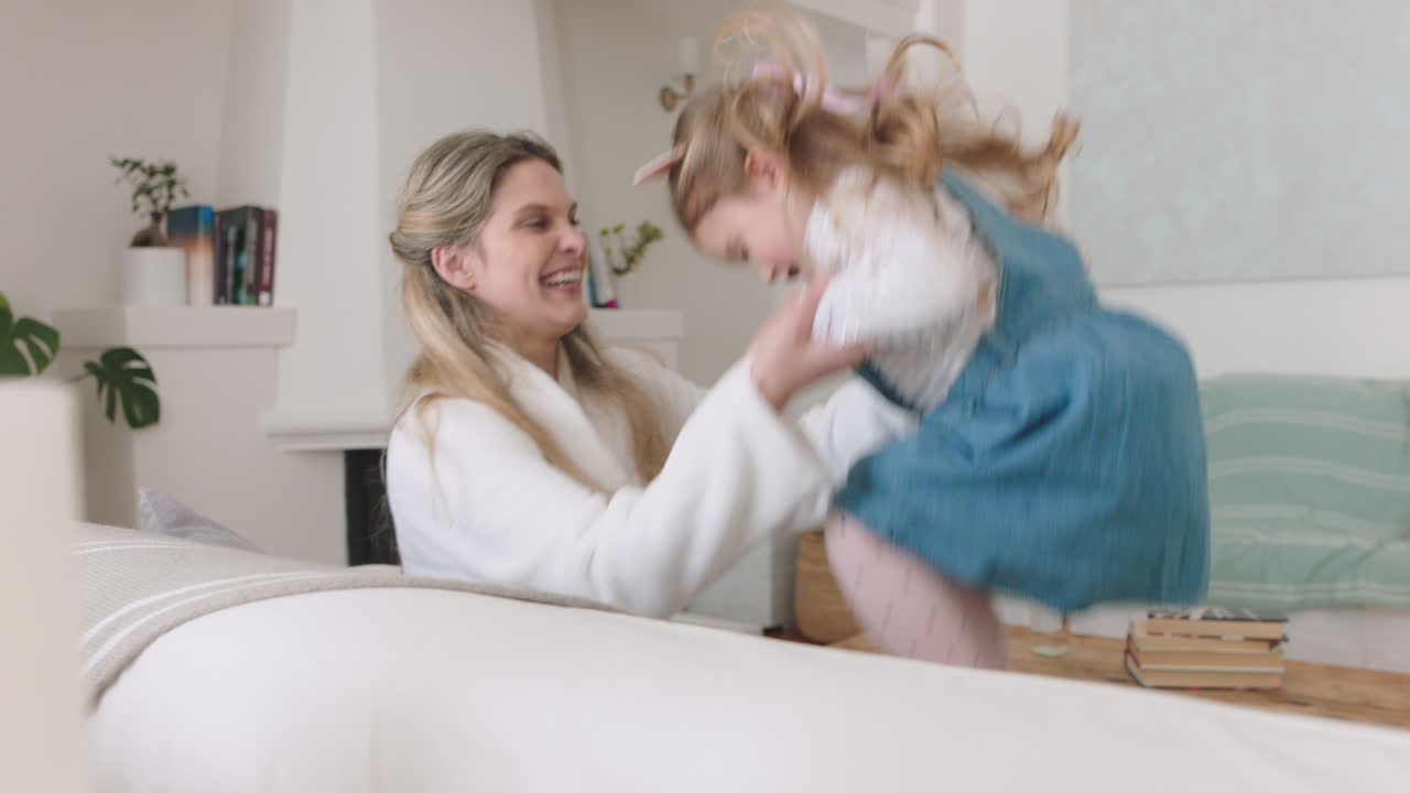 happy mother and daughter jumping on sofa little girl playing game with mom enjoying fun weekend together 4k footage