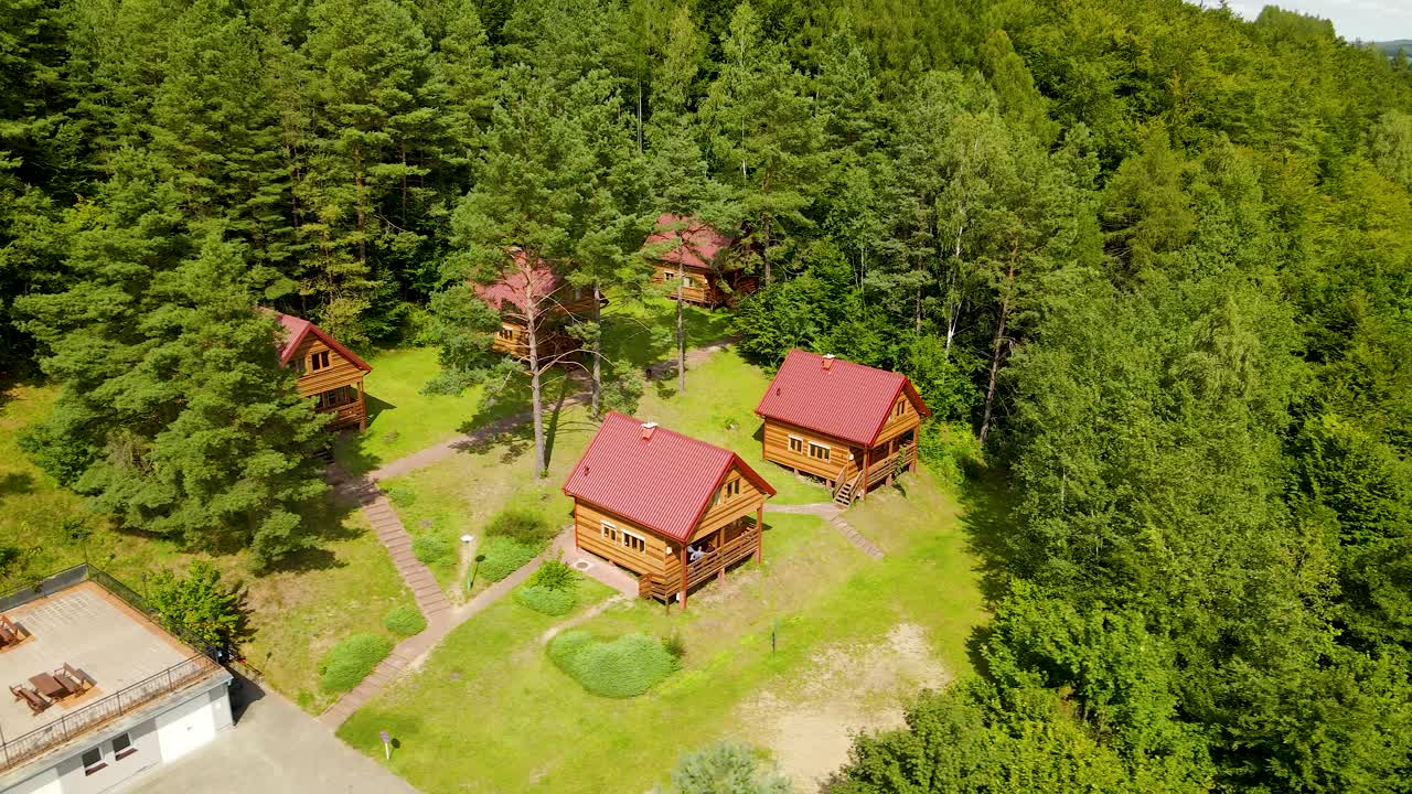 toma aérea de casas de vacaciones de madera en el bosque junto al lago radunksie dolne en polonia, borucino