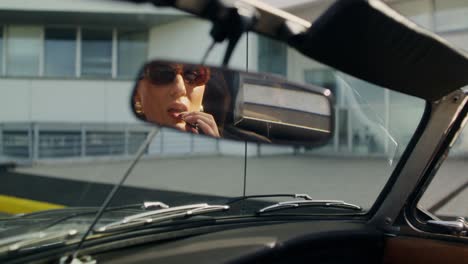 mujer aplicando lápiz labial en un coche de época