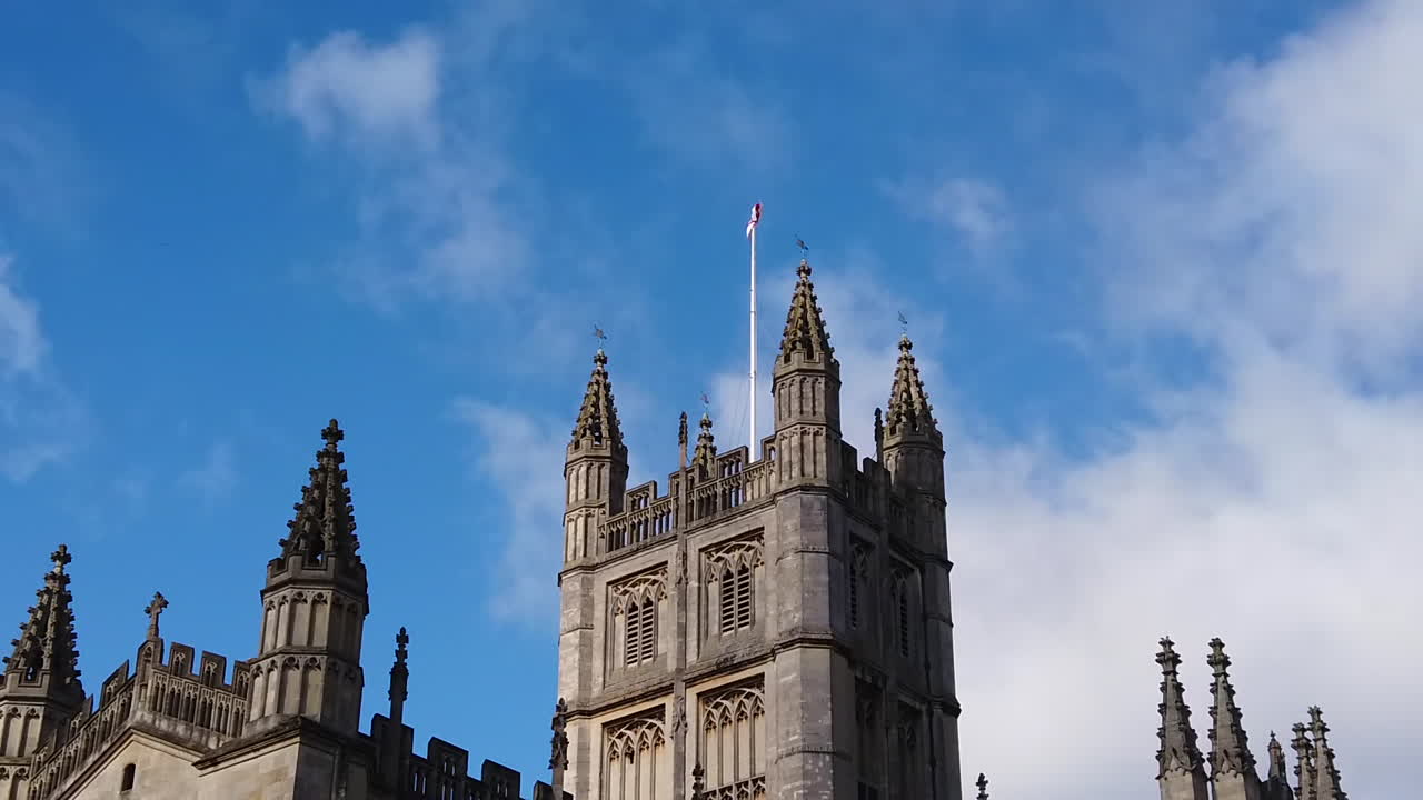 Super Slow Motion Shot of Saint George’s Cross Flapping in the Wind on top of the Tower of Bath Abbey in Somerset, England on Sunny Summer’s Day