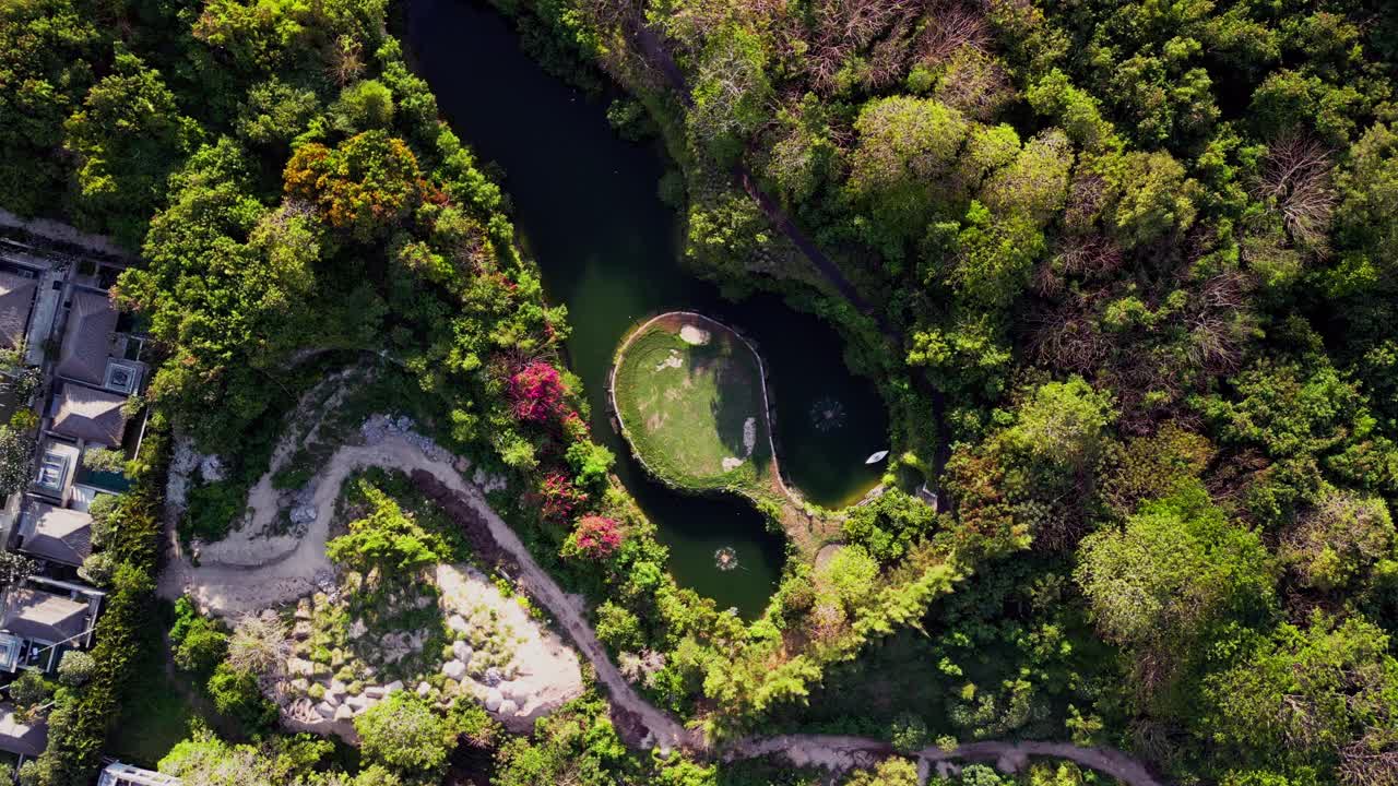 Drone footage captures a lush golf course island surrounded by tranquil water and tropical greenery in Nusa Dua, Bali. A peaceful scene blending luxury, sport, and the beauty of nature