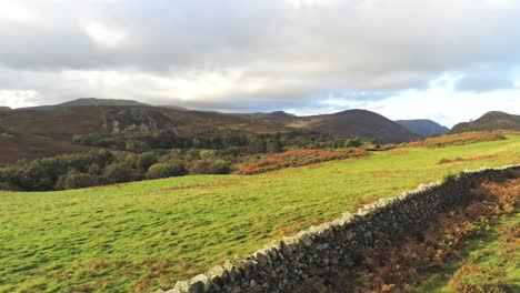 slow aerial dolly across british stone wall mountain valley rural farmland countryside