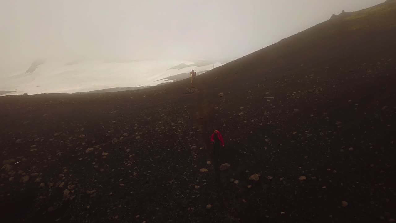 vista aérea de una persona caminando por un sendero de montaña, en un día nublado, área de fimmvörðuháls, islandia