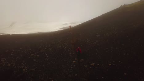 Aerial-view-of-a-person-hiking-on-a-mountain-trail,-on-a-foggy-day,-Fimmvörðuháls-area,-Iceland