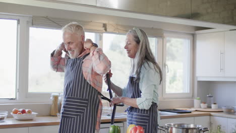 Middle-aged-caucasian-couple-putting-apron,-cooking-in-kitchen-at-home,-slow-motion