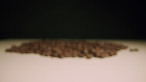 dolly towards pile of brown, roasted coffee beans on white table