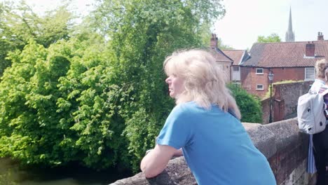 blonde haired woman looks over bishops stone bridge with norwich cathedral spire in background