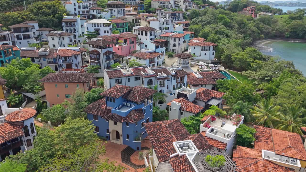 Zoom in aerial view of the colorful rooftops and lush green surroundings of Las Catalinas town, Costa Rica.