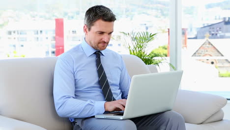 businessman typing on laptop sitting on sofa