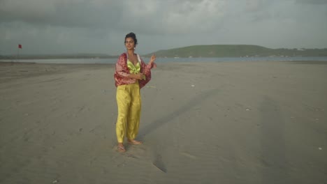 una fotografía impresionante capta a una joven vestida creativamente abrazando el clima de la costa con ráfagas, sosteniendo alegremente una cuerda de cometa en su mano
