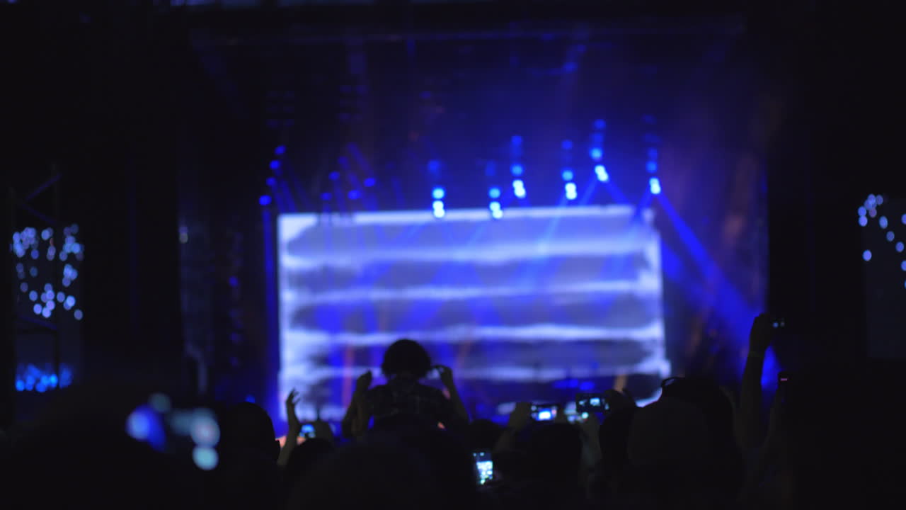 Un rallentatore di una folla davanti al palco illuminato a un concerto all'aperto