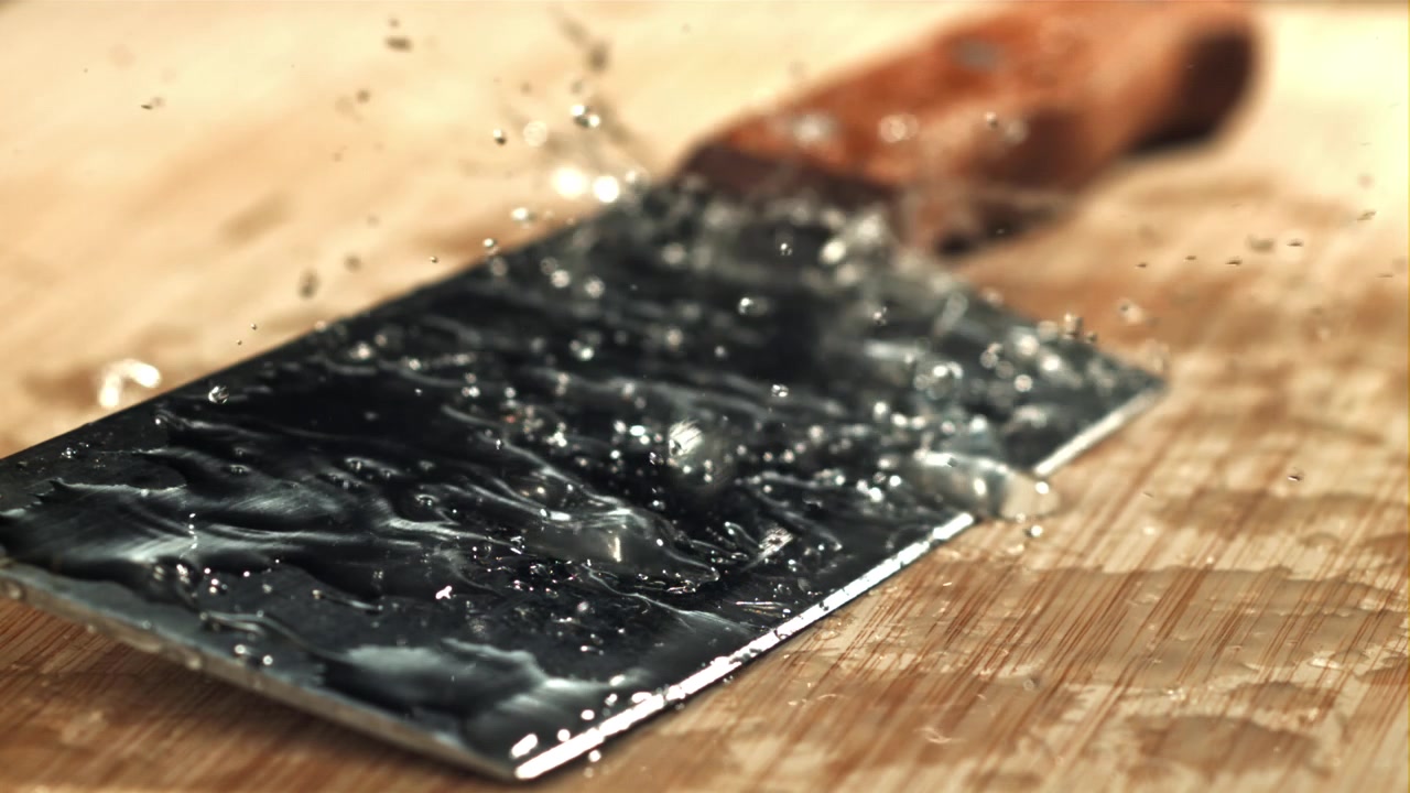 Slow Motion Water Drops Splashing on a Kitchen Knife Blade