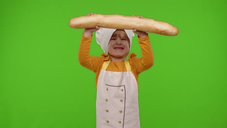 Child-girl-dressed-in-apron-like-chef-cook-baker-breaking-and-eating-fresh-baguette-on-chroma-key