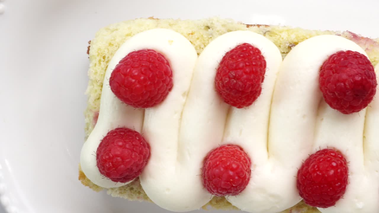 Making a dessert called Red Raspberry Tea Cake made with fresh berries and vanilla buttercream frosting. Great for Tea Parties. Close up video of red raspberry teacake passing by. Eating fresh cake