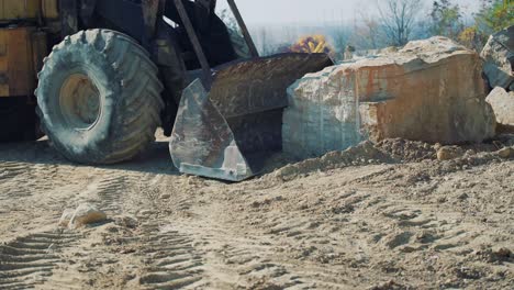 an old bulldozer moves a large stone on a quarry. close-up
